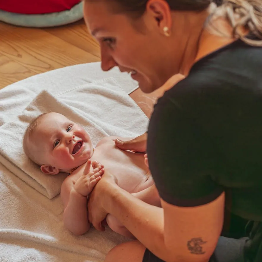 Lachendes Baby bei der Babymassage im Hotel