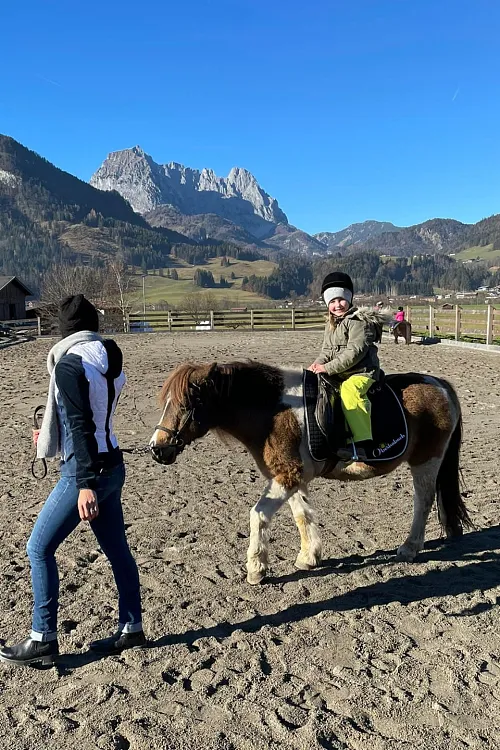 Kind reitet auf einem Pony vor herrlichen Bergkulisse in Tirol, Region