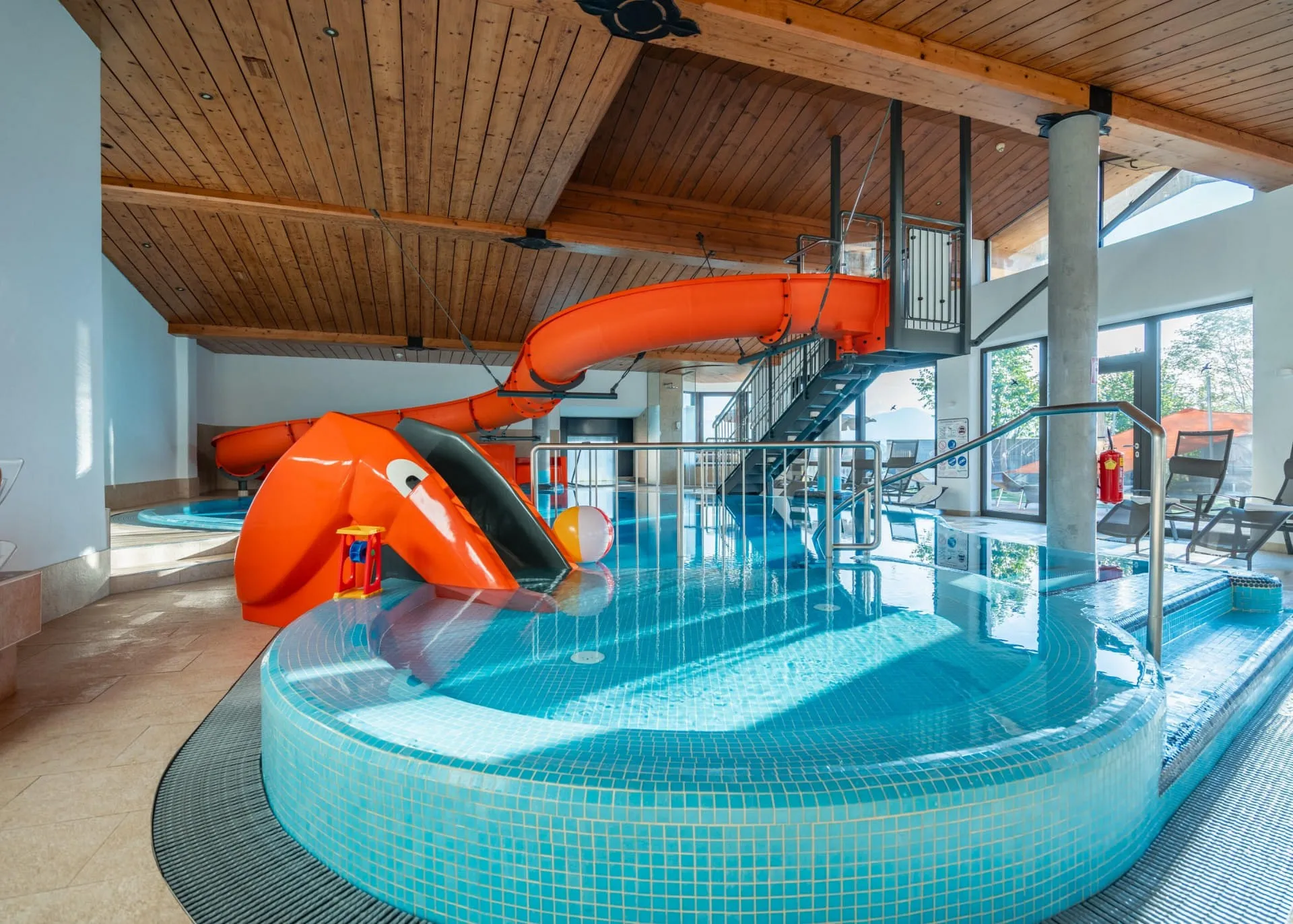 Innenansicht des Hallenbads mit Wasserrutsche im Familienhotel